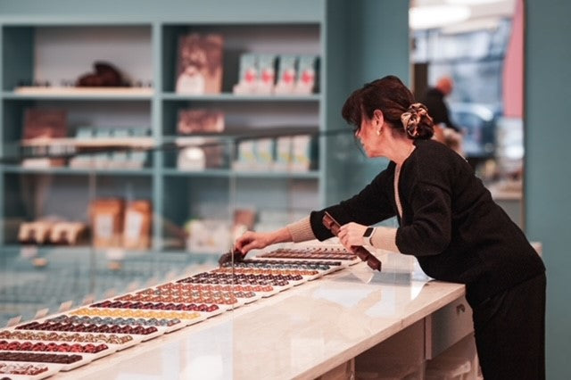 Person giving chocolates out of bonbon bar